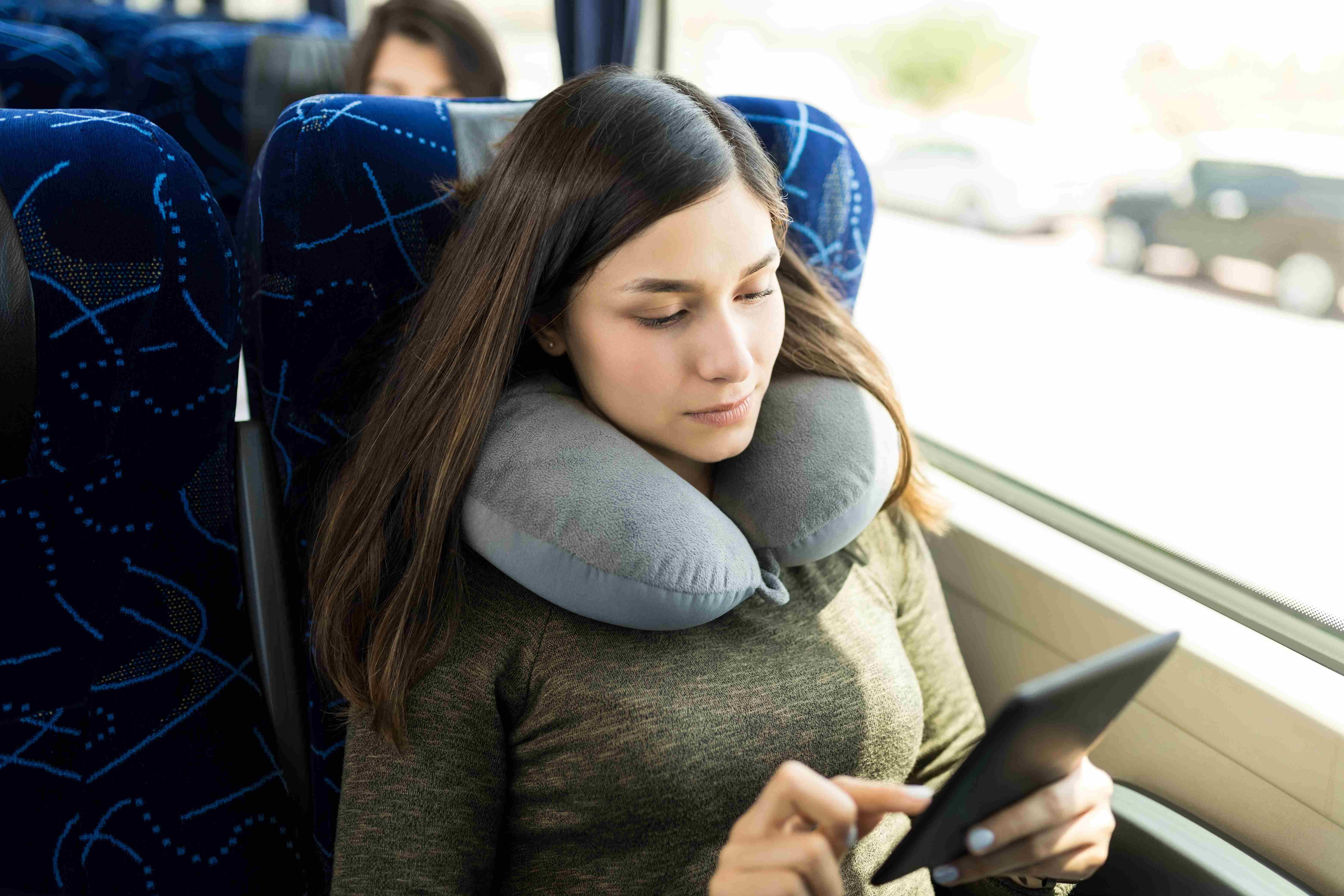 Photo of a young woman using a tablet while traveling in the bus